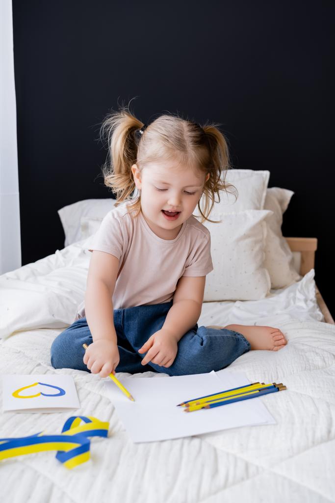 šťastná dívka kresba s barevnou tužkou v blízkosti stuhy a karty s modrým a žlutým srdcem  - Fotografie, Obrázek