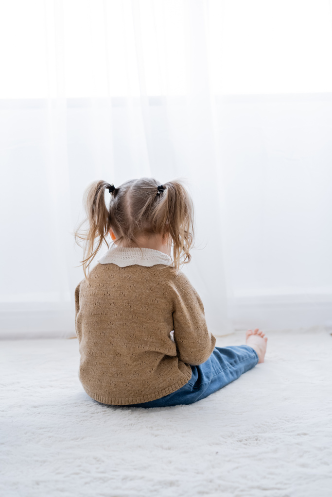 visszapillantás sértett kislány copfos ül a padlón otthon  - Fotó, kép