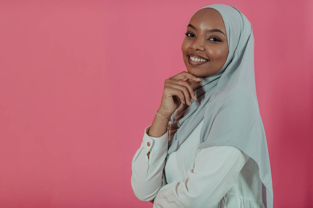 Retrato de la joven belleza afro musulmana moderna usando ropa islámica tradicional sobre fondo rosa plástico. Enfoque selectivo  - Foto, imagen
