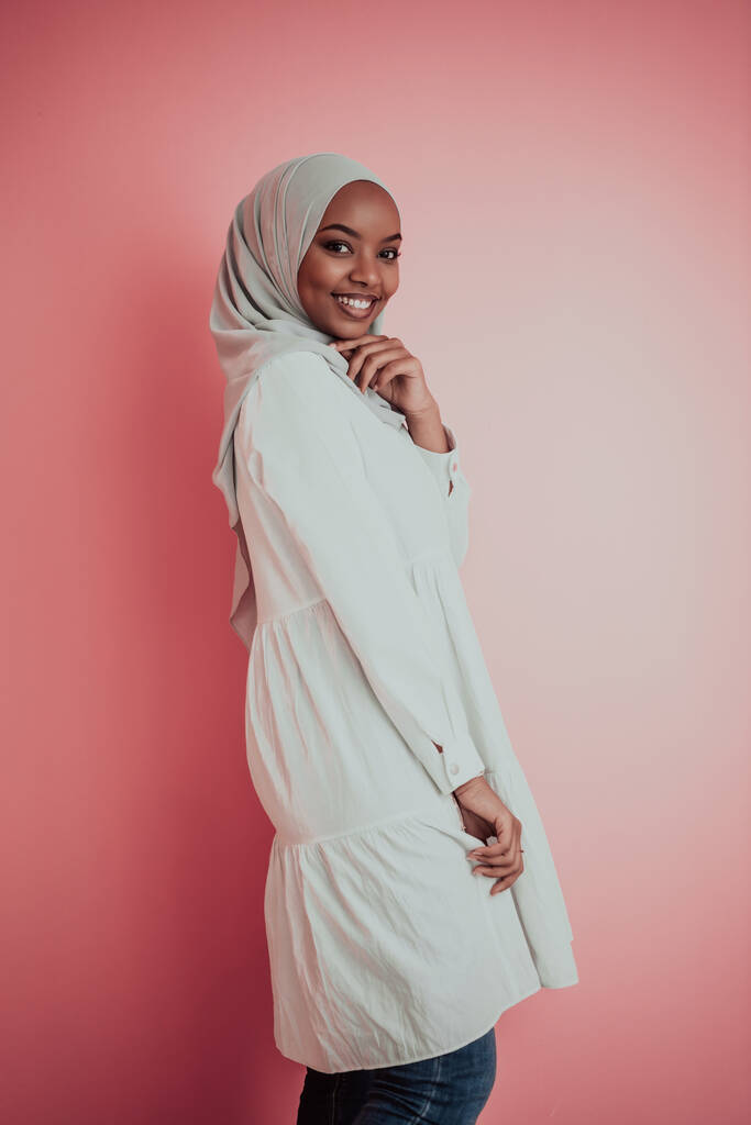 Retrato de la joven belleza afro musulmana moderna usando ropa islámica tradicional sobre fondo rosa plástico. Enfoque selectivo  - Foto, Imagen