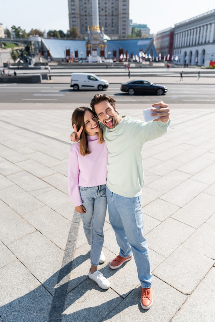 Positiivinen pari elehtii ja ottaa selfie kaupunkien kadulla  - Valokuva, kuva