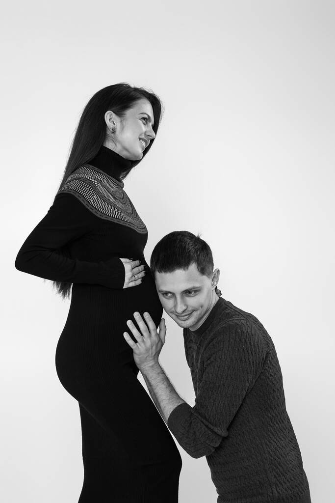 чоловік слухає свої молоді красиві вагітні дружини животик
 - Фото, зображення
