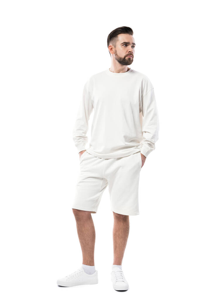 Jóképű férfi fehér hosszú ujjú pólót és rövidnadrágot visel, fehér alapon elszigetelve. - Fotó, kép