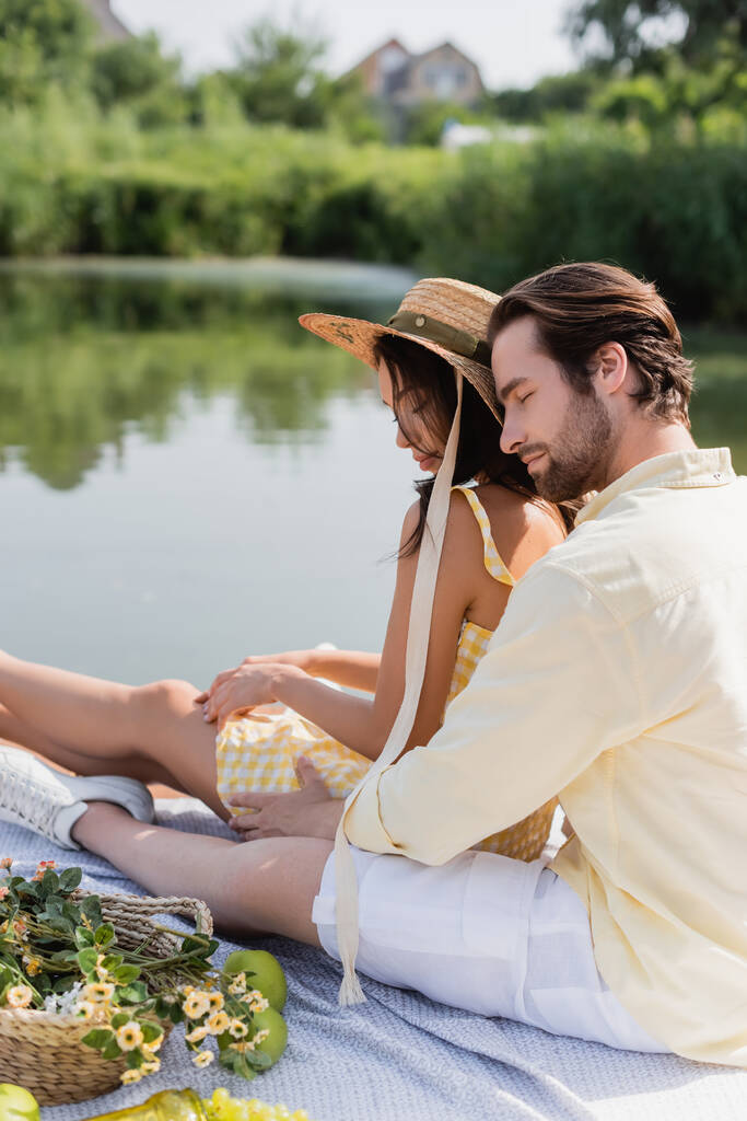 ρομαντικό ζευγάρι κάθεται στην προβλήτα κοντά στη λίμνη κατά τη διάρκεια πικ νικ - Φωτογραφία, εικόνα