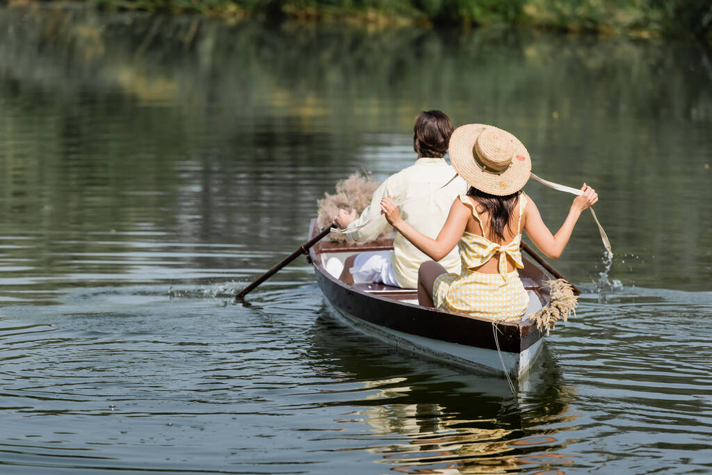Hasır şapkalı bir kadının erkek arkadaşıyla tekne turuna çıkması.   - Fotoğraf, Görsel