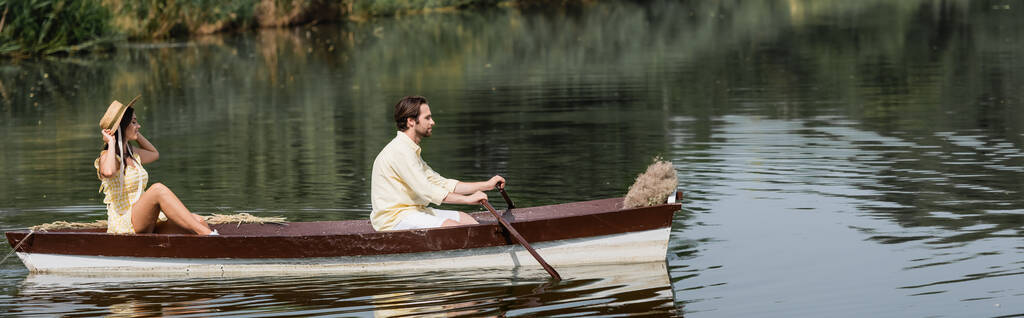 πλαϊνή άποψη του ζευγαριού έχοντας ρομαντική βόλτα βάρκα στη λίμνη, πανό - Φωτογραφία, εικόνα