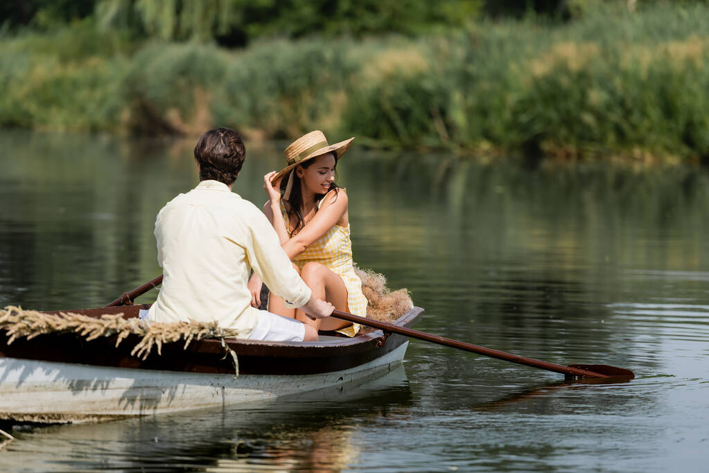 男とロマンチックなボートに乗るわら帽子の楽しい女性  - 写真・画像