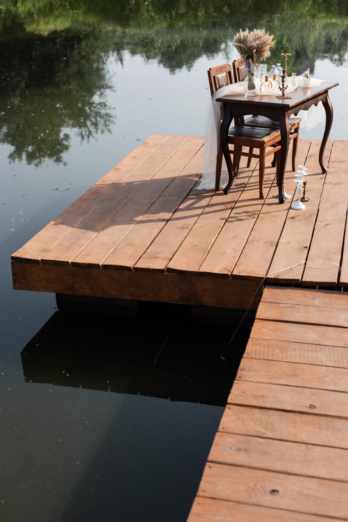 ensemble de table romantique pour le dîner sur une jetée en bois près du lac - Photo, image