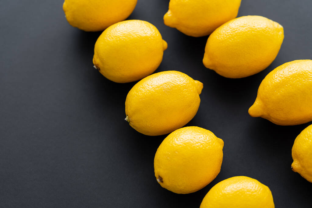 Flache Lage von saftigen und hellen Zitronen auf schwarzem Hintergrund  - Foto, Bild