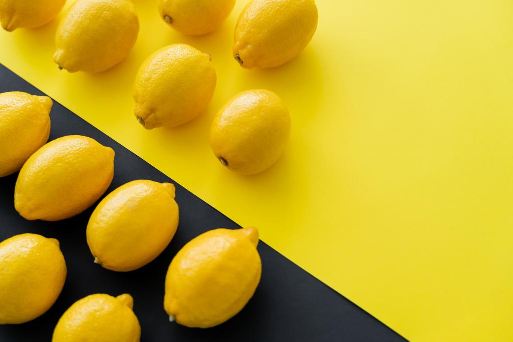Επίπεδη lay με φωτεινά λεμόνια σε κίτρινο και μαύρο φόντο  - Φωτογραφία, εικόνα