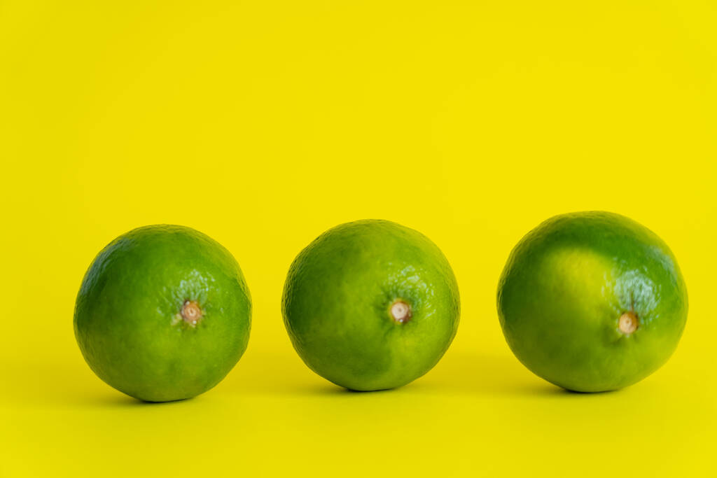 Ripe limes on yellow surface with copy space - Фото, изображение
