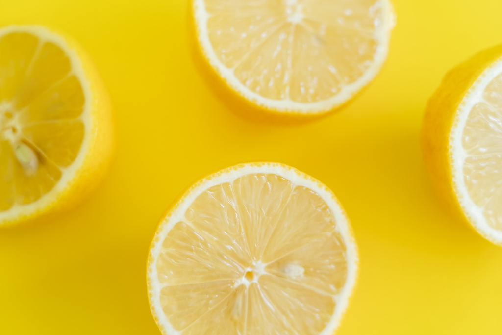 Top view of halves of ripe lemons on yellow background  - Zdjęcie, obraz