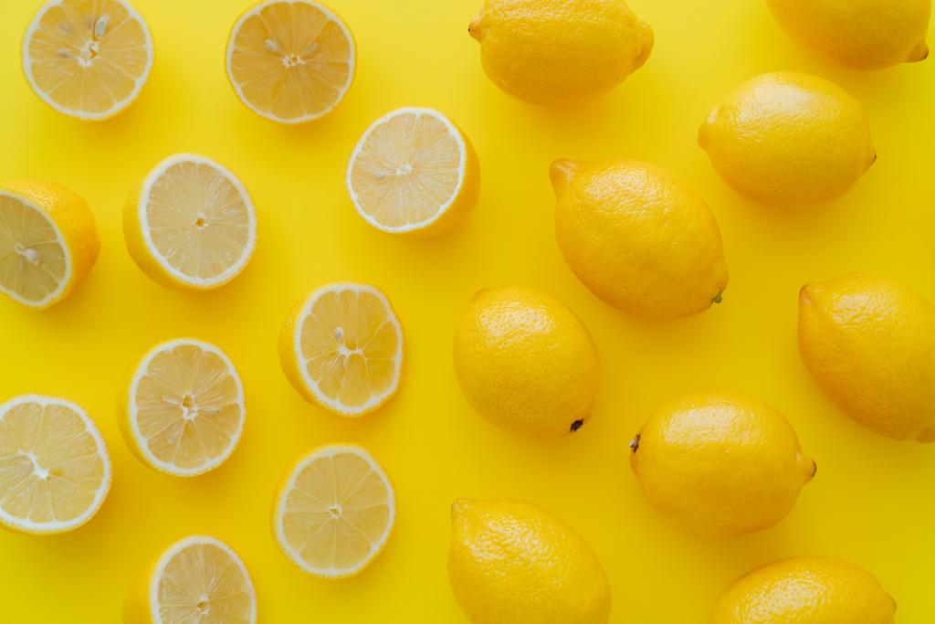 Flat lay with halves and whole lemons on yellow surface  - Zdjęcie, obraz