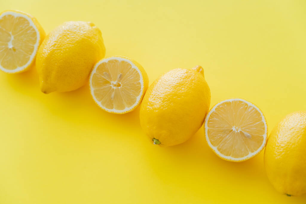 Flat lay with halves and whole lemons on yellow surface  - Zdjęcie, obraz