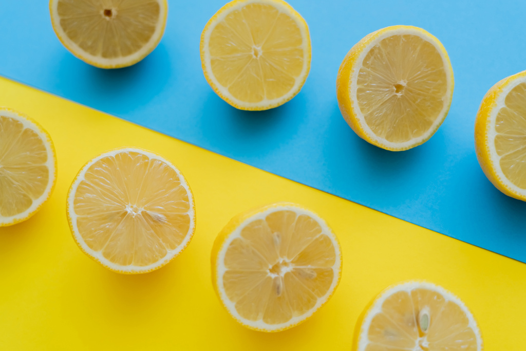 Вид зверху на свіжі нарізані лимони на синьо-жовтому фоні
  - Фото, зображення