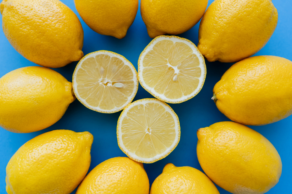 Top view of cut lemons in center of round on blue background - Foto, immagini
