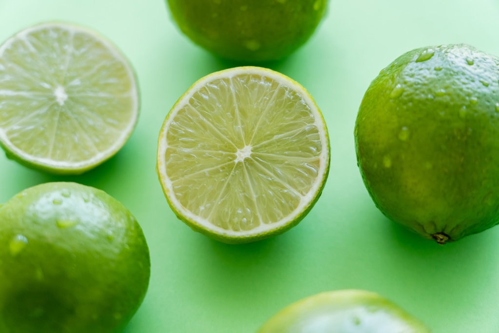 Close up view of juicy limes with water drops on green background - Foto, Imagem