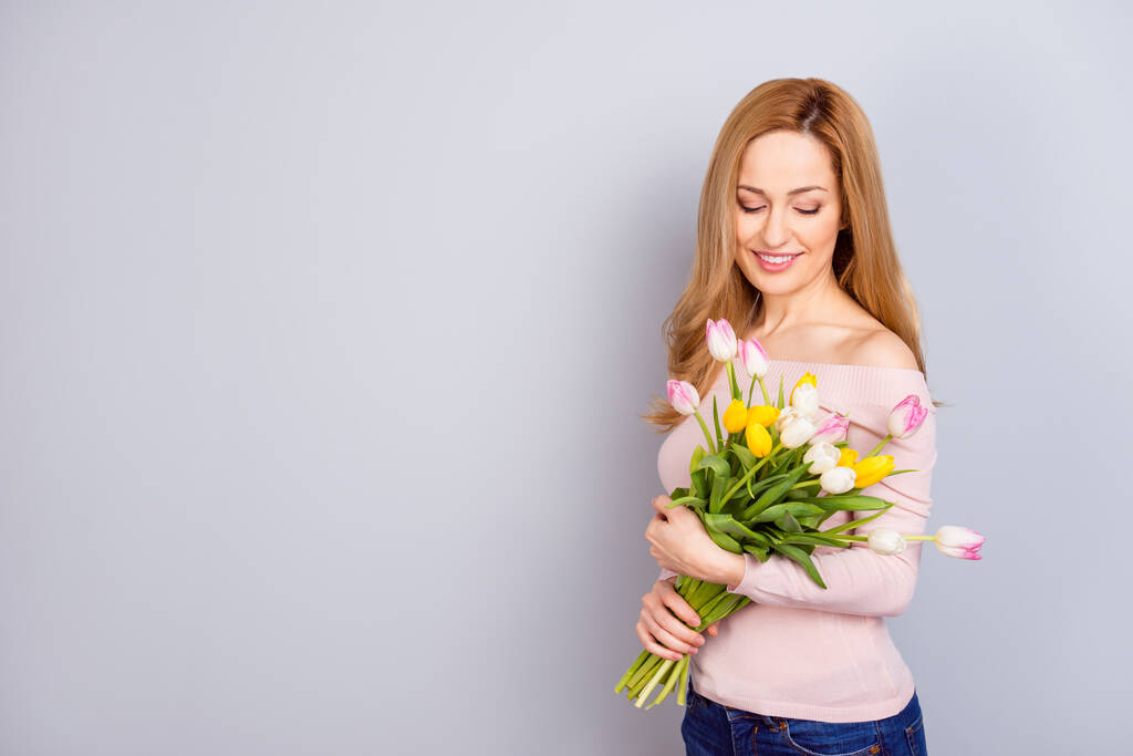 Foto de impresionante dama satisfecha sostiene flores frescas sonrisa dentada espacio vacío en blanco aislado sobre fondo de color gris - Foto, imagen