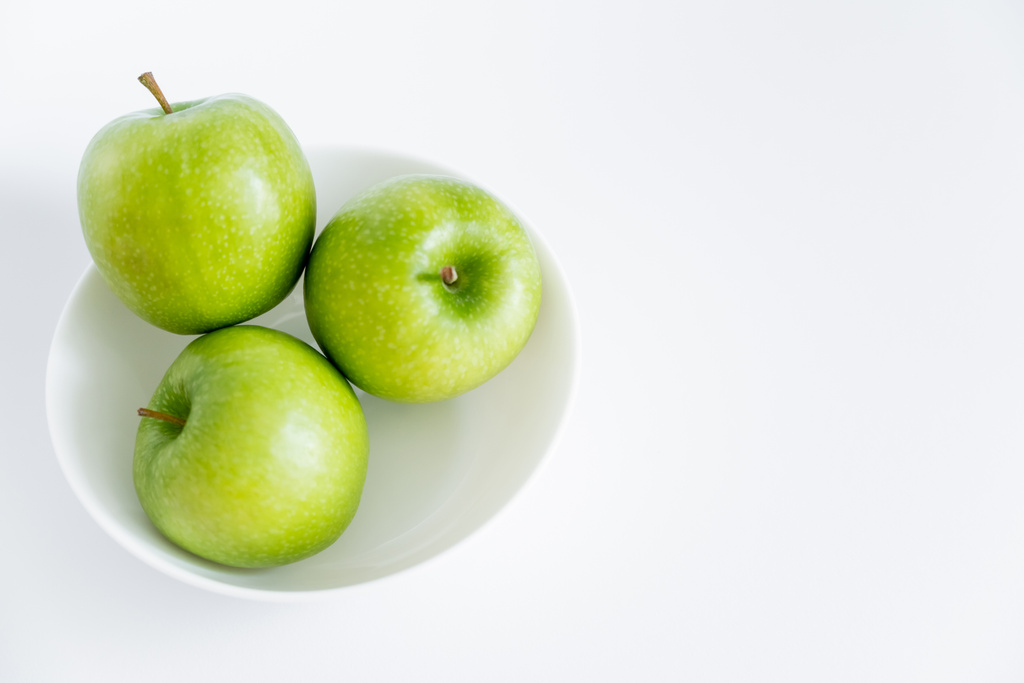 vista superior de manzanas verdes y maduras en tazón sobre blanco - Foto, imagen