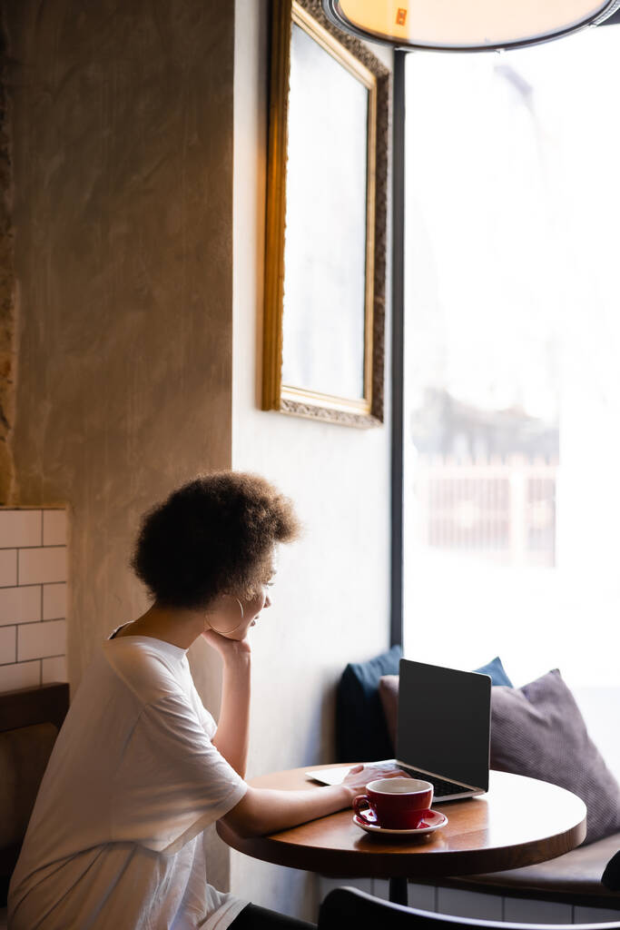 Genç Afrikalı Amerikalı kadın kafenin yanında boş ekran kahve kullanıyor.  - Fotoğraf, Görsel