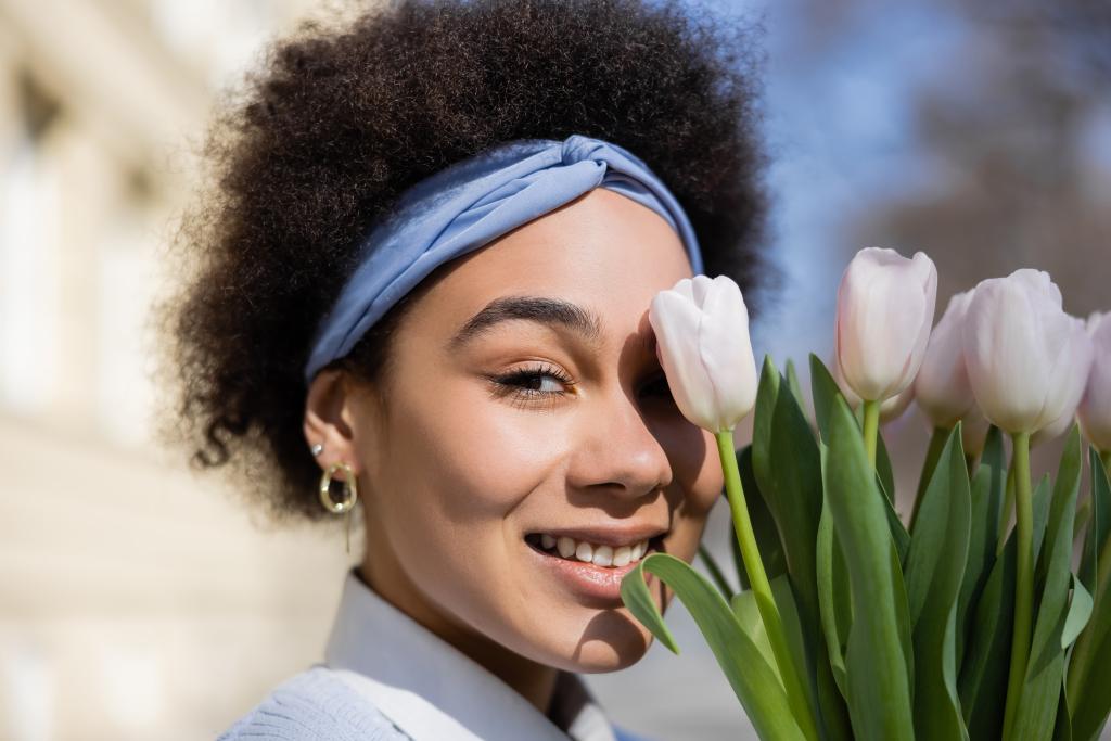 positive young african american woman looking at camera near bouquet of tulips - Fotoğraf, Görsel