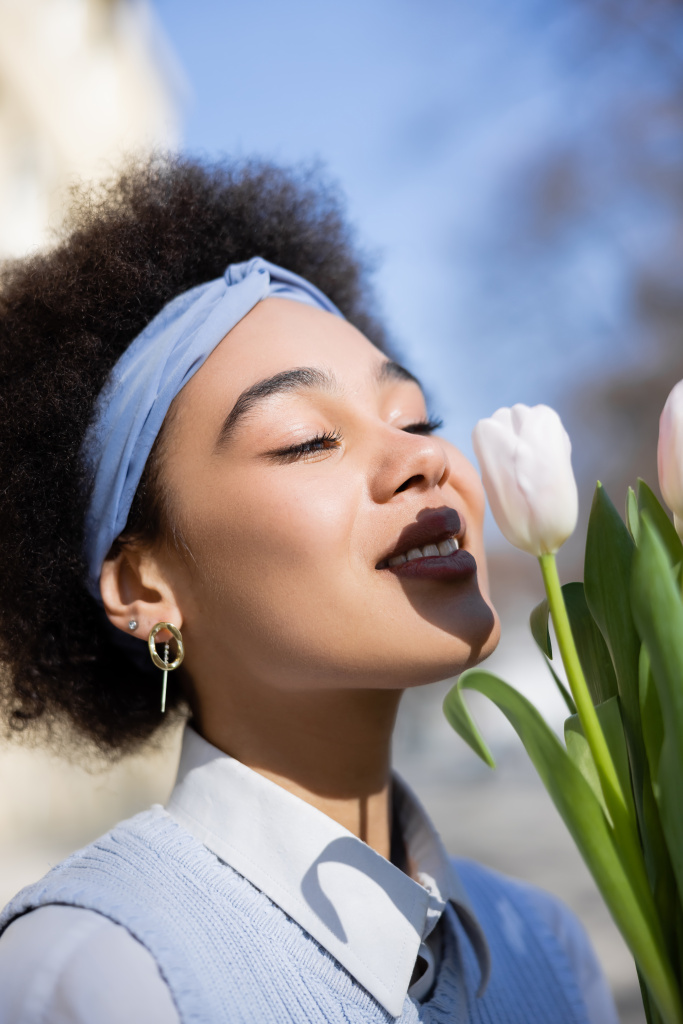 positief jong Afrikaans amerikaans vrouw op zoek boeket van tulpen - Foto, afbeelding