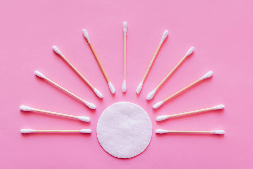 flat lay of ear sticks around white cotton pad on pink background, top view - Fotó, kép