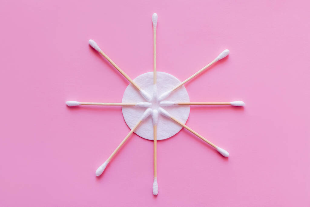 flat lay of cosmetic ear sticks near white cotton pad on pink background, top view - Foto, afbeelding