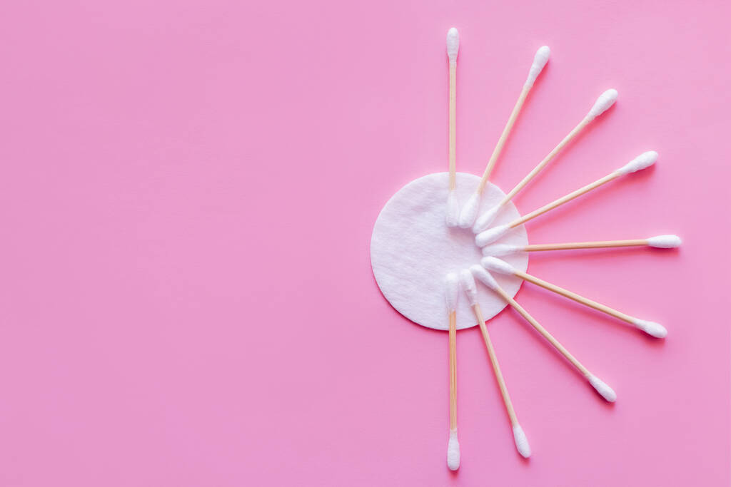 top view of hygienic ear sticks near white cotton pad on pink background - Valokuva, kuva