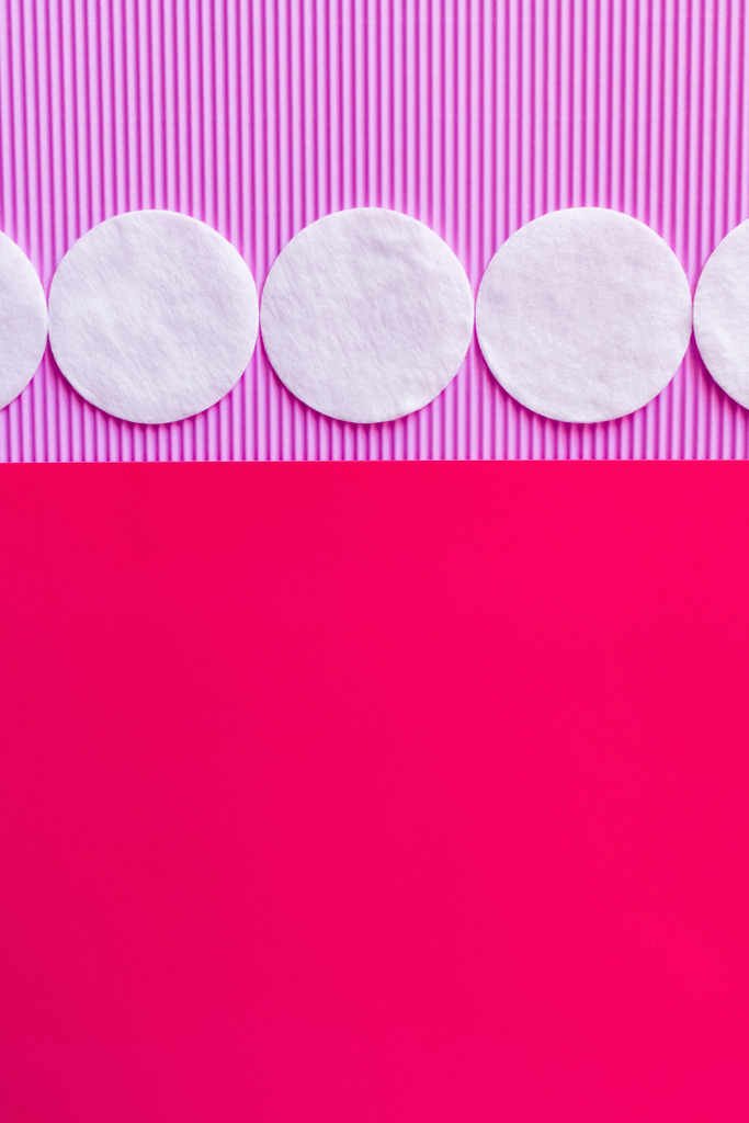 horizontal row of cotton pads on bicolor violet and pink background, top view - Fotoğraf, Görsel
