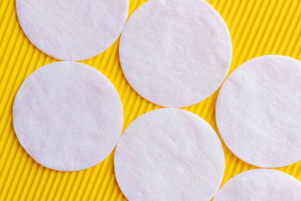 close up of white cotton pads on yellow textured background, top view - Fotó, kép