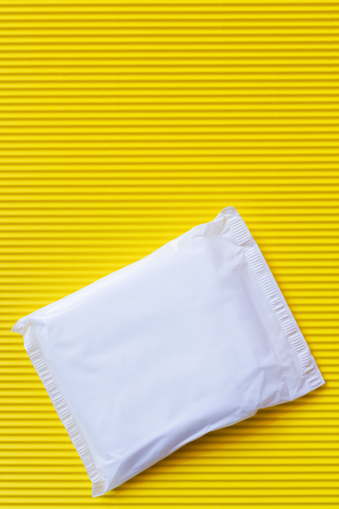 horní pohled na zabalené kalhotky liner na texturovaném žlutém pozadí - Fotografie, Obrázek