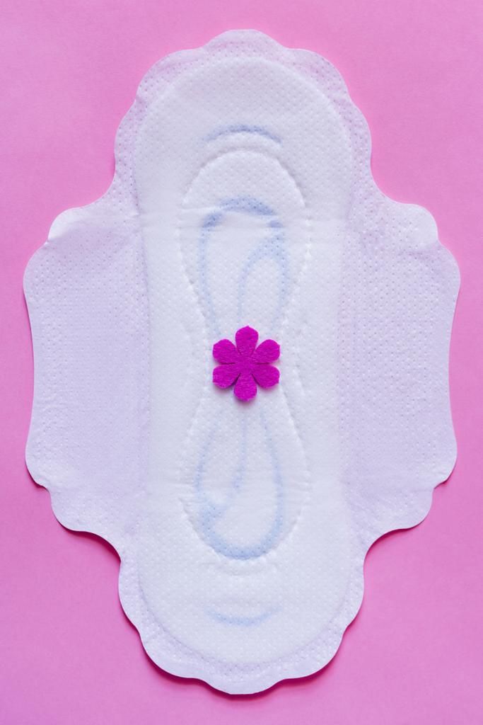 top view of white panty liner with purple flower on violet background - Foto, Imagen