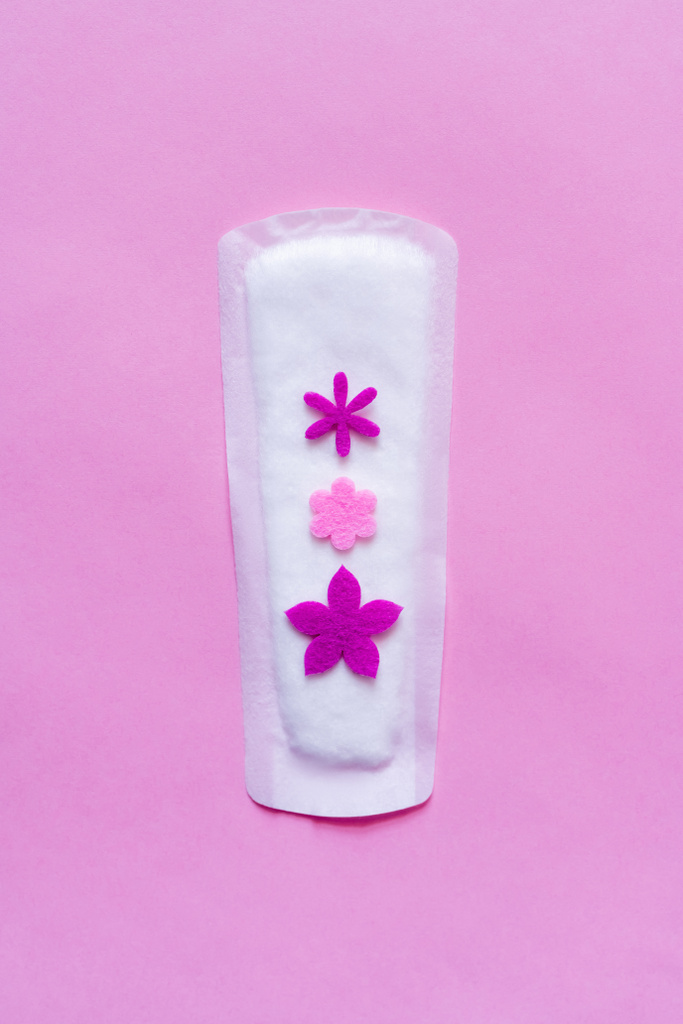 top view of white panty liner with decorative flowers on violet background - 写真・画像