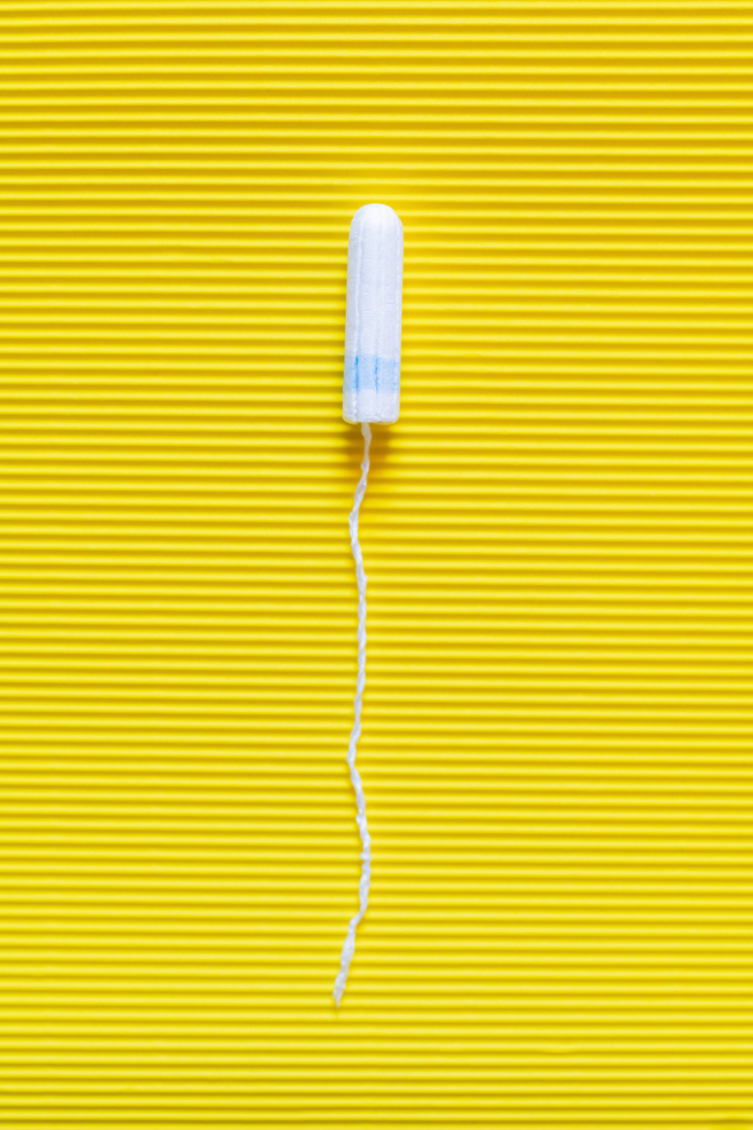 top view of hygienic tampon on bright yellow textured background - Foto, imagen
