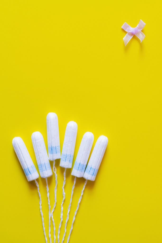 top view of tampons and bow on yellow background with copy space - Fotó, kép