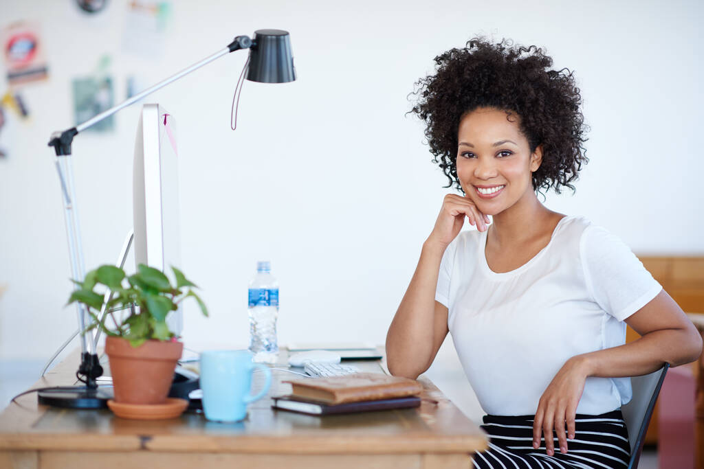 Portrét atraktivní mladé ženy sedící na svém pracovišti v kanceláři. Komerční vzory zobrazené v tomto obrázku představují simulaci reálného produktu a byly změněny nebo změněny - Fotografie, Obrázek