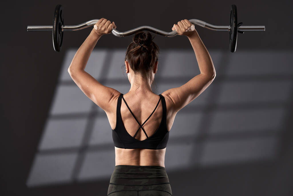 Kobieta robi trening mięśnia naramiennego z zakrzywioną sztangą - Zdjęcie, obraz