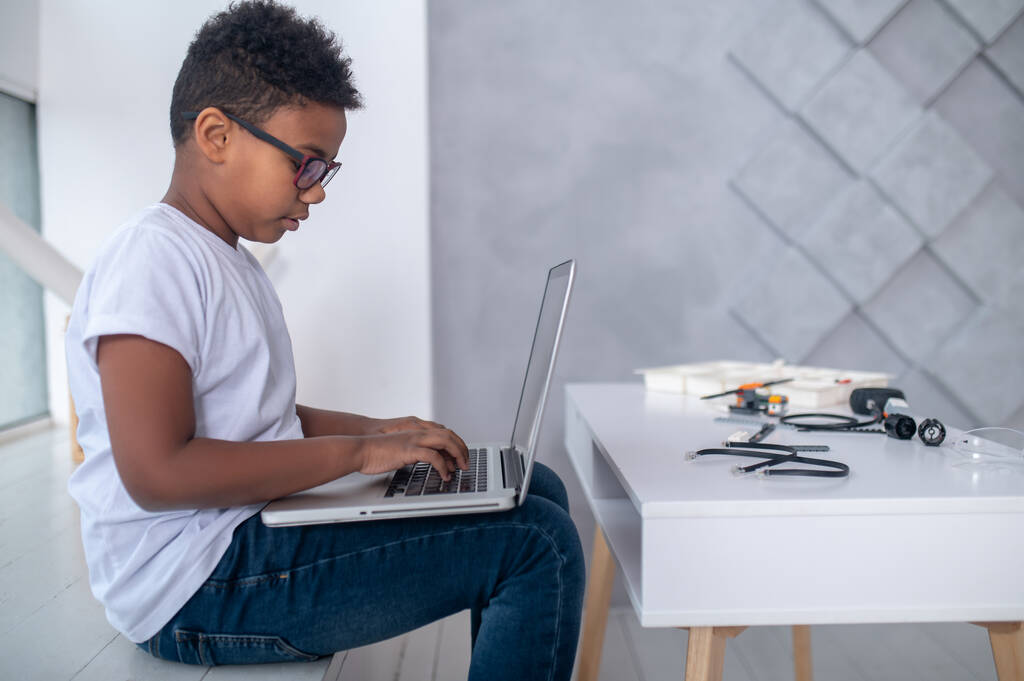 Söpö teini istuu kannettavan tietokoneen ääressä ja etsii mukana - Valokuva, kuva