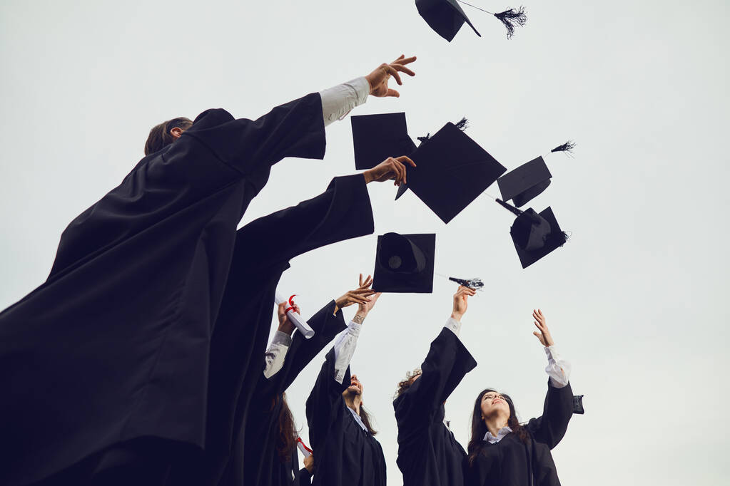 Les diplômés jettent leur chapeau académique dans le ciel lors d'une cérémonie solennelle à l'université. - Photo, image