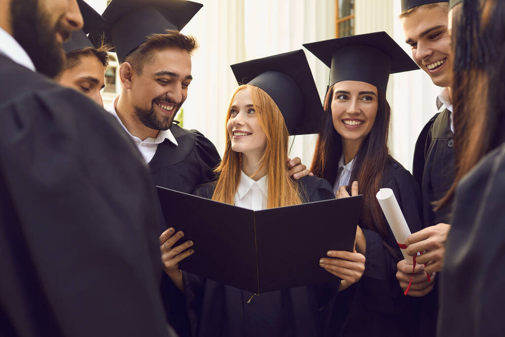 Skupina usměvavých absolventů vysokých škol, kteří společně stojí s diplomy a slaví promoci - Fotografie, Obrázek
