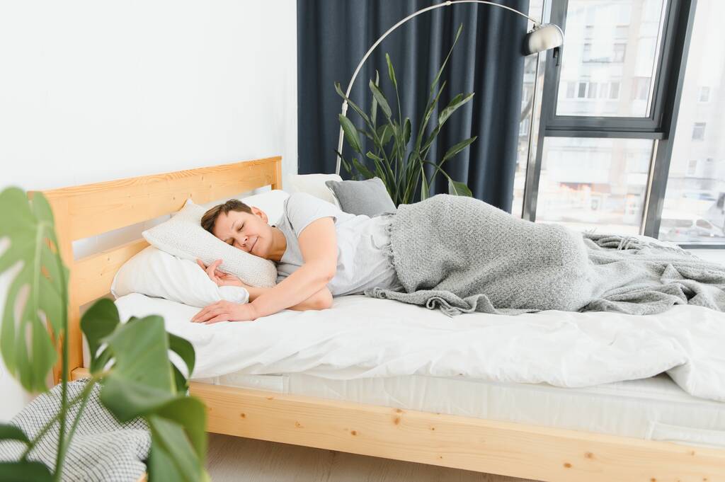 Frau schläft im Bett unter weißer Decke mit Kopf auf Kopfkissen. - Foto, Bild
