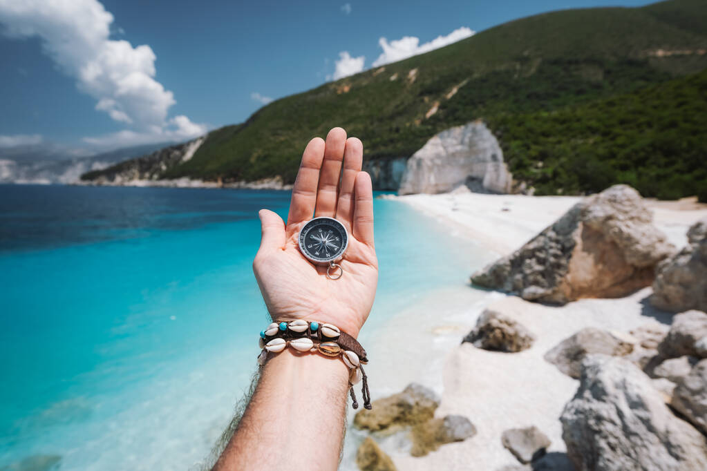 Hand houden van een kompas op het strand op de achtergrond. - Foto, afbeelding