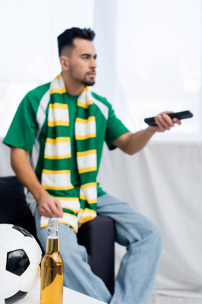 selective focus of soccer ball and beer near blurred sports fan clicking tv channels - Photo, Image