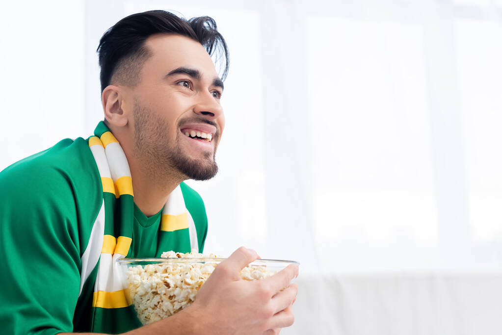 joyful sports fan with popcorn watching championship at home - Foto, Imagen