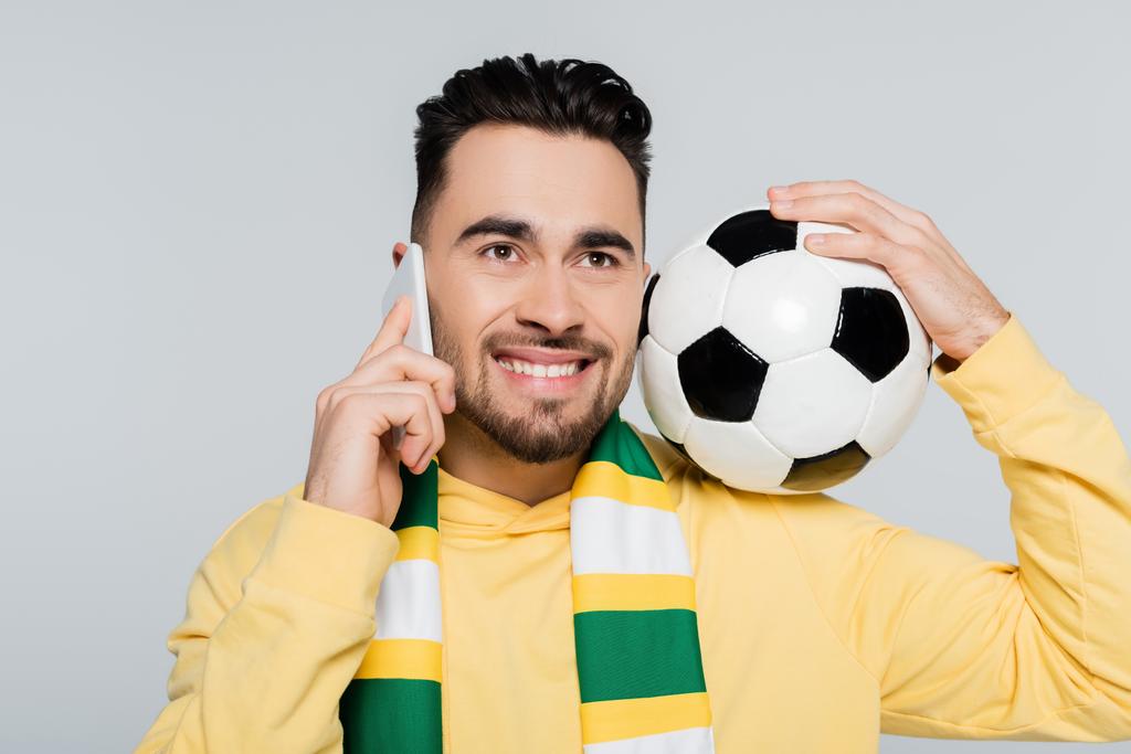 torcedor de futebol alegre em cachecol listrado falando no telefone celular isolado no cinza - Foto, Imagem
