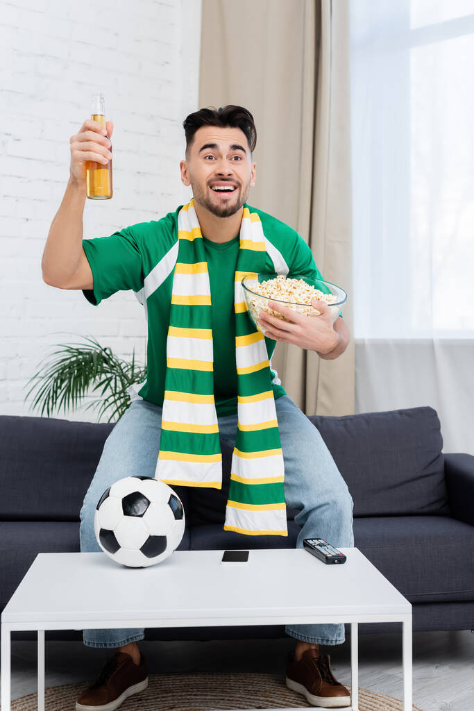 cheerful sports fan with beer and popcorn watching championship near soccer ball - Fotografie, Obrázek