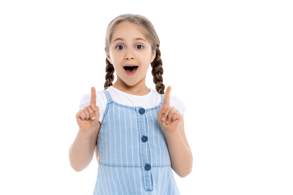 užaslá dívka v modrém popruh šaty ukazuje nahoru s prsty izolované na bílém - Fotografie, Obrázek
