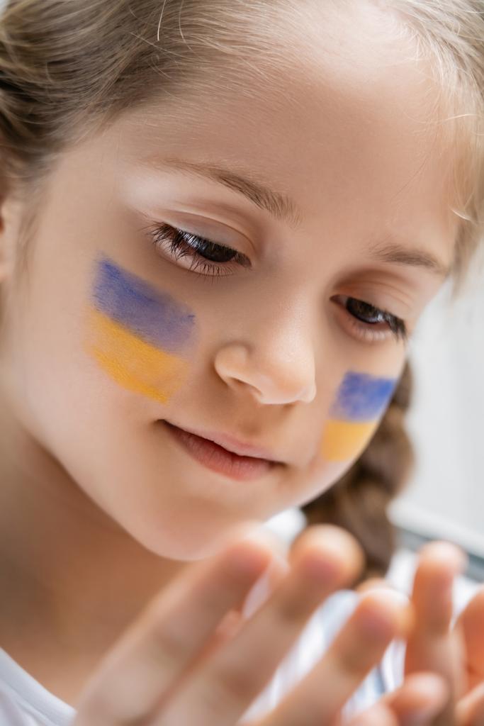 Yüzünde Ukrayna bayrakları olan vatansever kızın portresini kapat. - Fotoğraf, Görsel