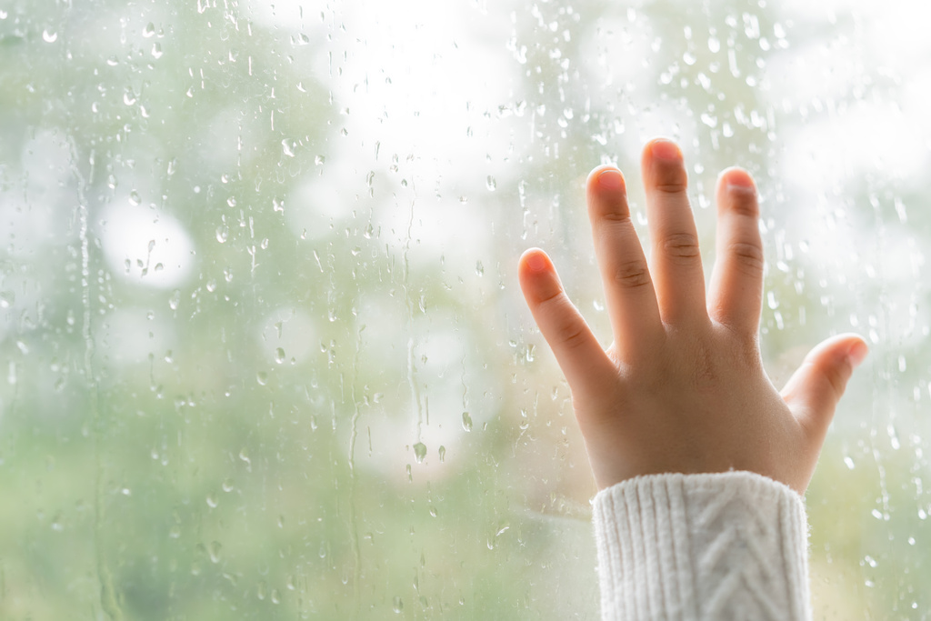 Pencereye yağmur damlalarıyla dokunan çocuğun kısmi görüntüsü - Fotoğraf, Görsel